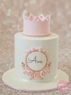 a white cake with pink frosting and a crown on top that says feliz cumpleanos