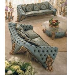 a living room filled with blue couches next to a table and flowers on the floor