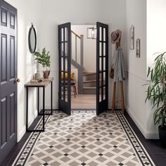 an entry way with black doors and tiled flooring, potted plants on either side