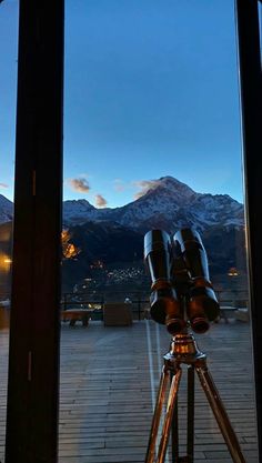 a telescope on a tripod in front of a mountain range at night with the sun setting