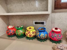 five brightly colored pots sitting on top of a counter