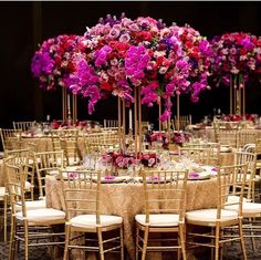 the tables are set with gold chairs and tall centerpieces filled with purple flowers