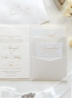 the wedding stationery is laid out on a white tablecloth with flowers in it