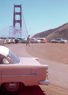 an old car is parked in front of the golden gate bridge