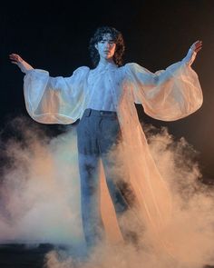 a man in white shirt and pants standing on stage with his arms spread wide open