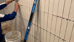 a man is painting a wall with blue paint and some buckets on the side