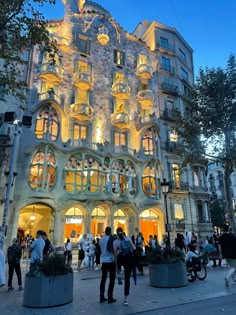 people are standing in front of a building with many windows and balconies at night