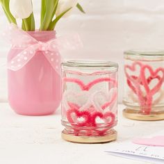 two mason jars with hearts painted on them, one is pink and the other has white tulips