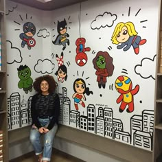 a woman sitting in front of a wall with cartoon characters on it