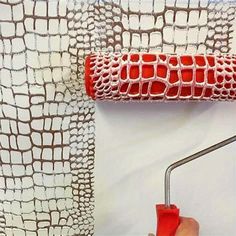 a person is using a paint roller to paint a wall with red and white patterns