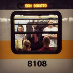 a group of people standing on the side of a subway train looking out the window