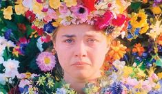 a man with flowers on his head standing in front of a bunch of flowers