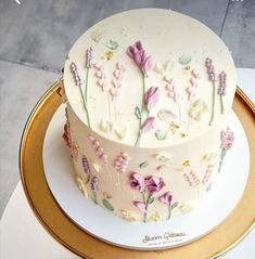 there is a white cake with flowers on the top and gold trimming around it