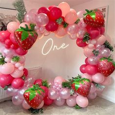 a strawberry balloon arch with pink and red balloons