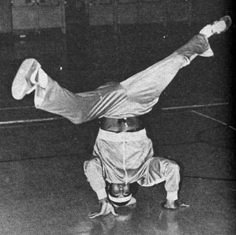 a man doing a handstand on top of a tennis racquet in an indoor court