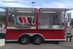 a red food truck parked in a parking lot with american flags on the side of it