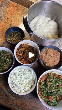 bowls filled with different types of food sitting on top of a wooden table next to a metal pan