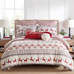 a christmas themed bed in a bedroom with red and white decorations on the comforter