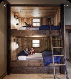 bunk beds with ladders are in the middle of a room that has wood paneling on the walls