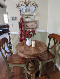 a wooden table with two chairs and a vase filled with flowers on top of it