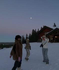 three people are walking in the snow at dusk