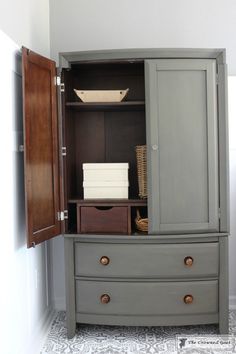 an armoire with drawers and baskets in the bottom drawer is painted gray, while another cabinet has brown doors