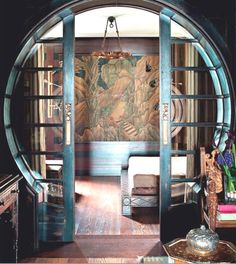 an open door leading to a living room with wood floors and walls, in front of a painting on the wall