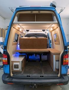 the back end of a blue van with an open trunk and dining table in it