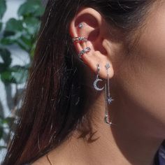 a close up of a person wearing some kind of earring with leaves in the background