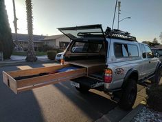 a white truck with an open bed is parked on the side of the road in front of some palm trees