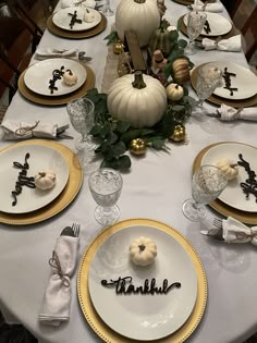 the table is set for thanksgiving dinner with white pumpkins and gold trimmings