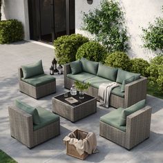 an outdoor patio furniture set with green cushions and pillows on the ground next to bushes