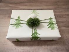 a present wrapped in white and green wrapping paper with a pine tree design on it