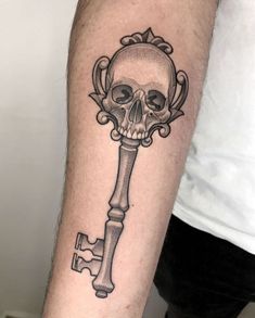 a skull and key tattoo on the arm