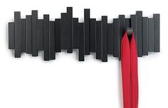 a red umbrella hanging from the side of a black and white wall with vertical bars attached to it