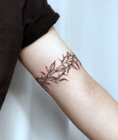 a woman's arm with a tattoo on it that has leaves growing out of it