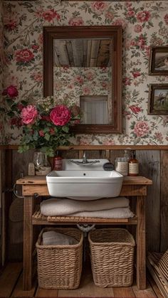 a white sink sitting under a mirror next to a wooden table with flowers on it