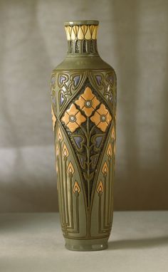 a green vase sitting on top of a table next to a white wall in the background