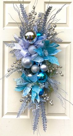 a wreath with blue and silver ornaments hanging on a door