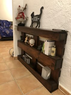 a book shelf sitting on the floor in front of a wall with books and stuffed animals