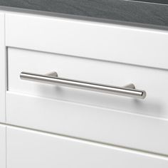 a close up of a drawer handle on a white cabinet with black counter top and drawers