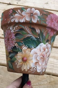 a hand holding an ice cream container with flowers painted on it