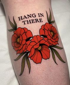 a woman's leg with red flowers and the words hang in there on it