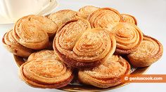 a plate full of pastries next to a cup of coffee on a white table