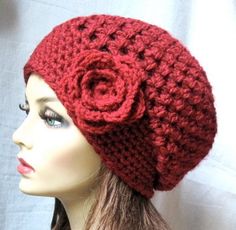 a mannequin head wearing a red knitted hat with a flower on it