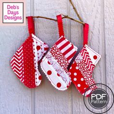 three red and white oven mitts hanging from a twig with polka dots on them