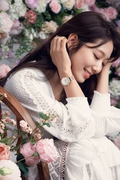 a woman sitting in a chair with her hand on her head and flowers behind her