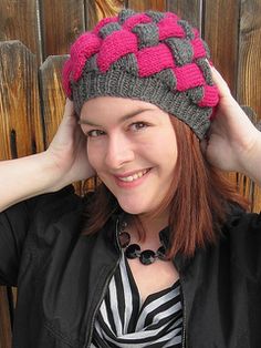 a woman wearing a knitted hat with pink and grey squares on it's brim