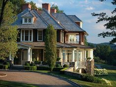 a large house with lots of windows on the front and side of it, surrounded by greenery