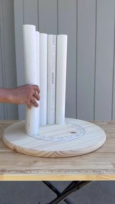 a person is holding some paper on top of a wooden table with four white poles